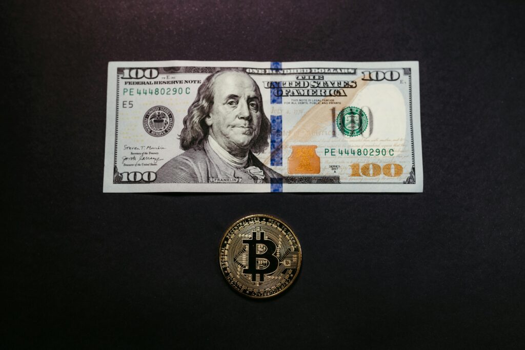 billete de 100 dolares junto con una moneda de bitcoin
